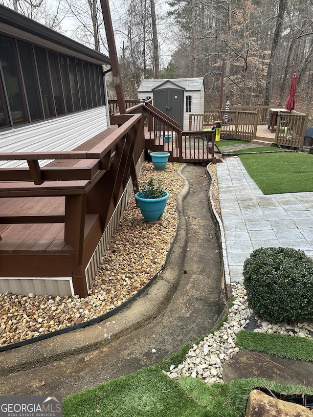 wooden terrace with a sunroom, an outdoor structure, and a storage unit