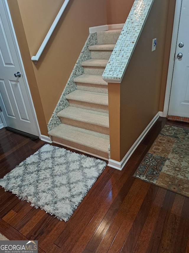 staircase with wood-type flooring and baseboards