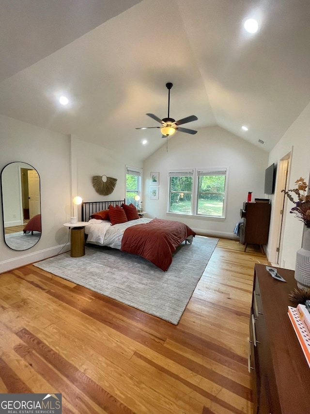 bedroom with multiple windows, ceiling fan, lofted ceiling, and light wood-type flooring