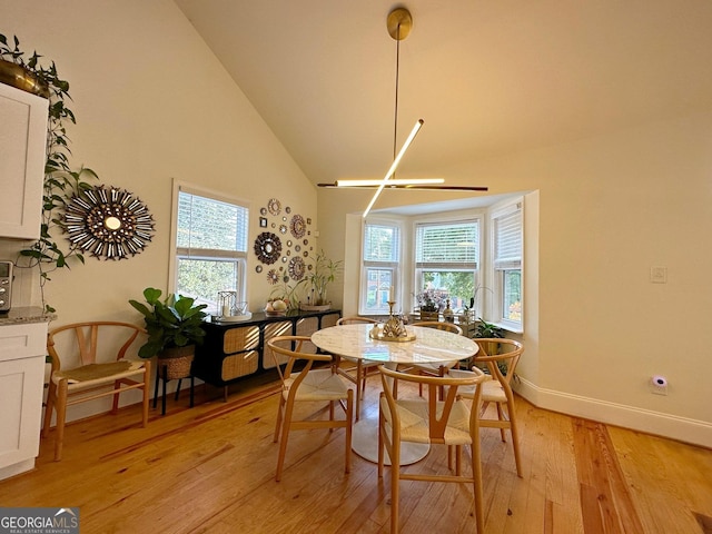 dining area with high vaulted ceiling and light wood-type flooring