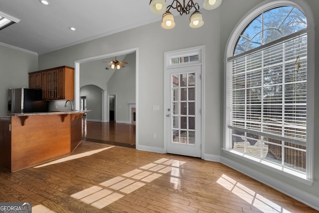 kitchen with a kitchen bar, hanging light fixtures, kitchen peninsula, stainless steel refrigerator with ice dispenser, and light hardwood / wood-style flooring