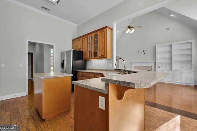 kitchen featuring a kitchen bar, sink, light wood-type flooring, kitchen peninsula, and a kitchen island