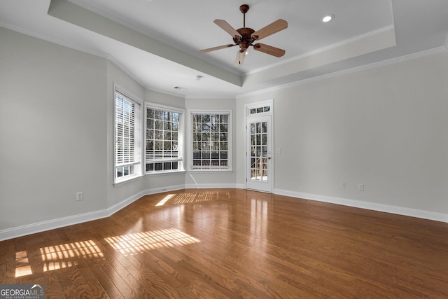 empty room featuring hardwood / wood-style flooring, ceiling fan, crown molding, and a raised ceiling