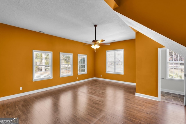 unfurnished living room with dark wood-type flooring, a textured ceiling, and a wealth of natural light