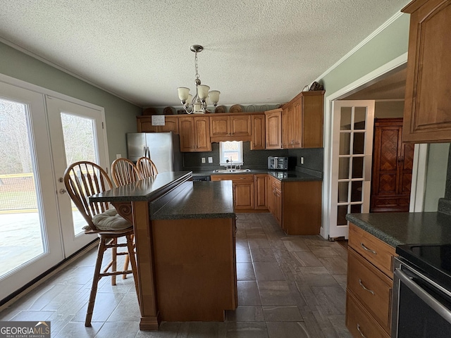 kitchen featuring sink, a breakfast bar area, an inviting chandelier, stainless steel refrigerator with ice dispenser, and a kitchen island