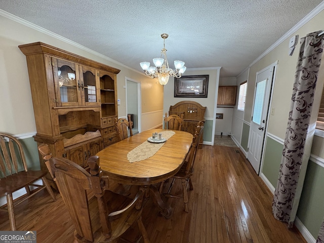 dining area with ornamental molding, dark hardwood / wood-style floors, a notable chandelier, and a textured ceiling