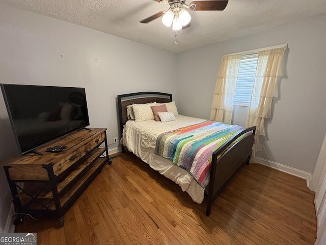 bedroom featuring wood-type flooring, ceiling fan, and a textured ceiling