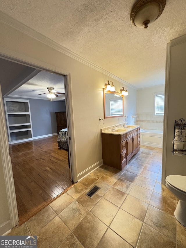 bathroom featuring crown molding, ceiling fan, vanity, a bath, and a textured ceiling