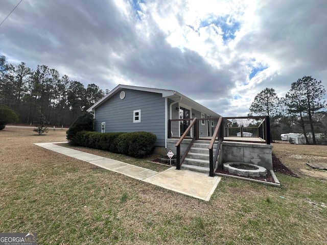 view of home's exterior with a fire pit and a lawn