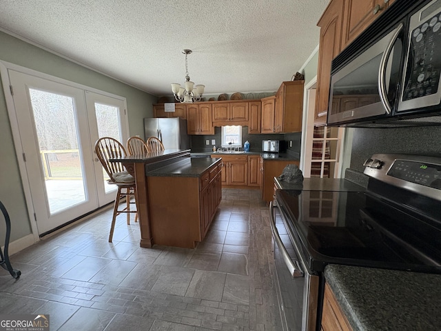 kitchen featuring a breakfast bar, decorative light fixtures, appliances with stainless steel finishes, a kitchen island, and a notable chandelier