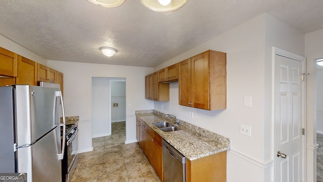 kitchen featuring sink, stainless steel appliances, a textured ceiling, and light stone countertops