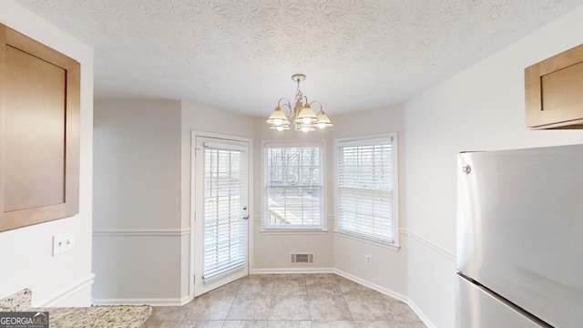 unfurnished dining area with a textured ceiling and a chandelier