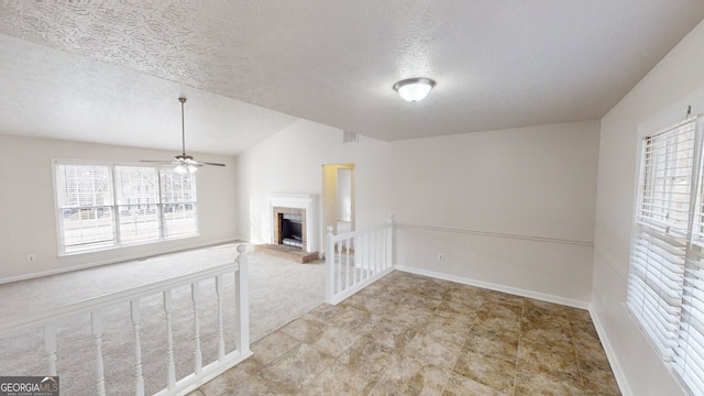 empty room with ceiling fan, a textured ceiling, and a fireplace