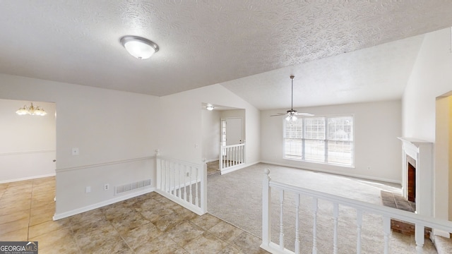 carpeted empty room featuring lofted ceiling, ceiling fan with notable chandelier, and a textured ceiling