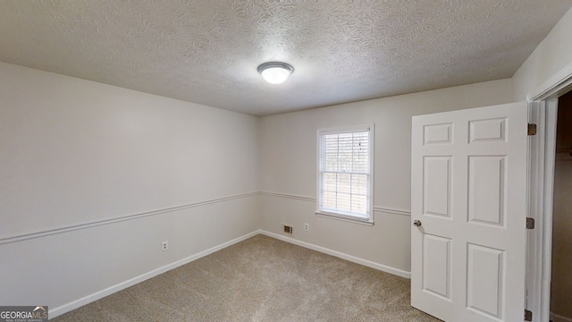 spare room with light carpet and a textured ceiling