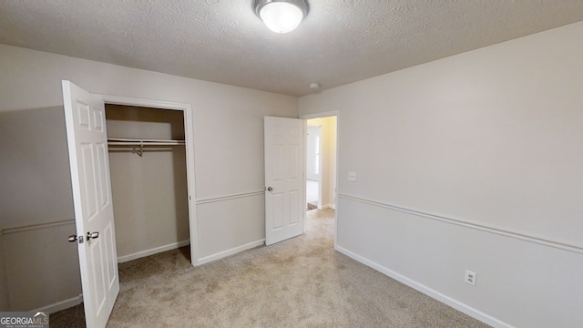 unfurnished bedroom featuring light colored carpet, a textured ceiling, and a closet