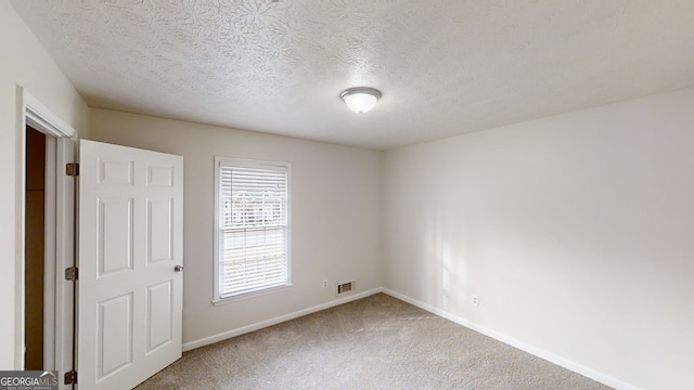 carpeted empty room with a textured ceiling