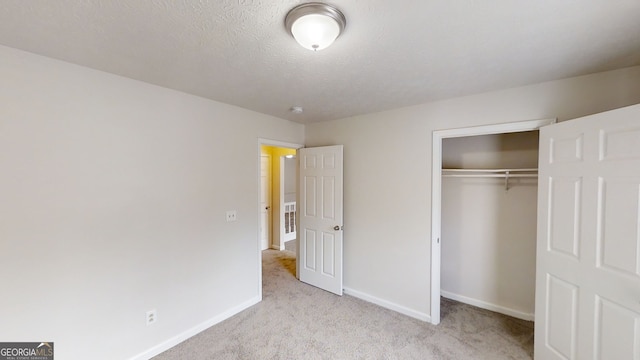 unfurnished bedroom featuring light colored carpet, a closet, and a textured ceiling