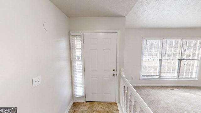 foyer with light carpet and a textured ceiling