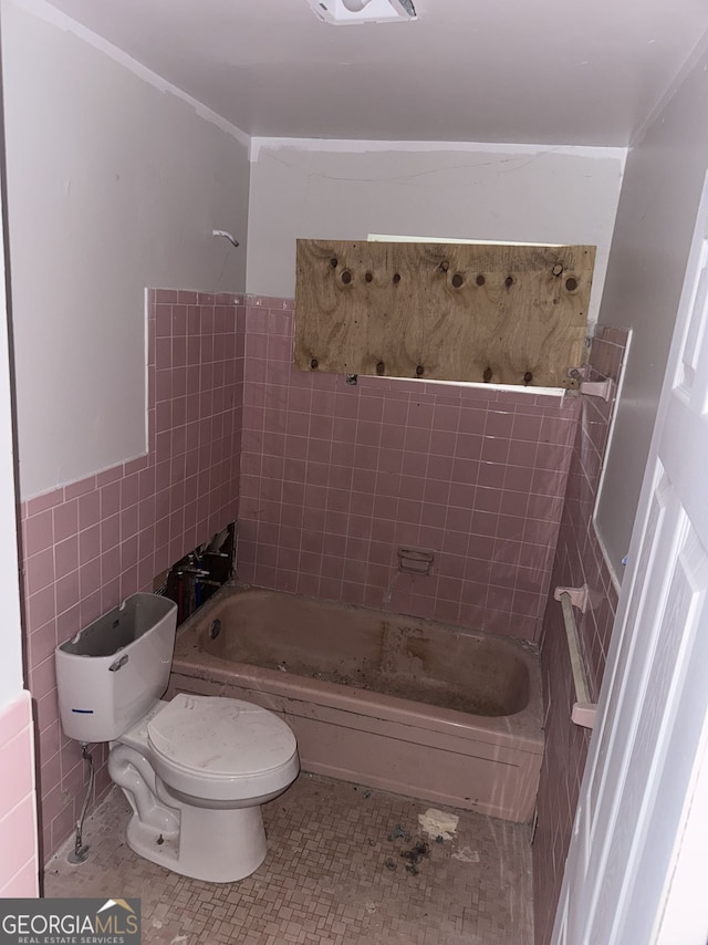 bathroom with toilet, tiled shower / bath combo, tile patterned flooring, and tile walls