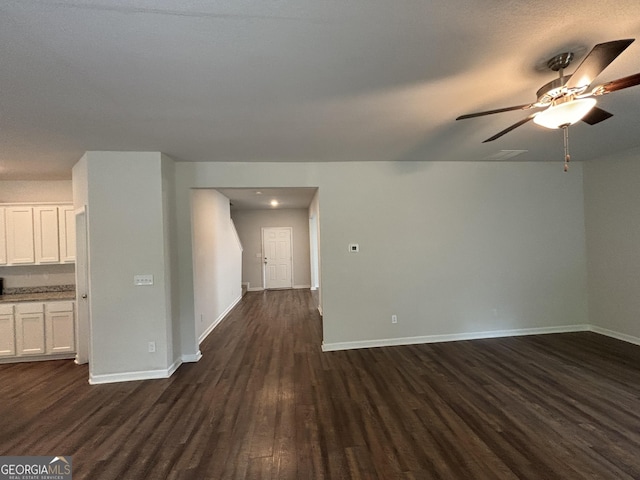 unfurnished living room with dark hardwood / wood-style flooring and ceiling fan