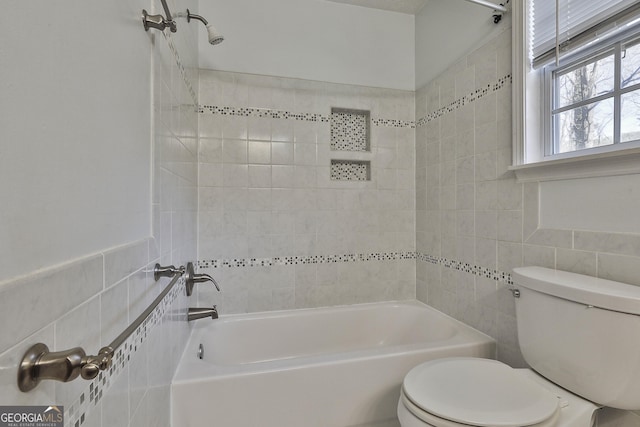 bathroom with tile walls, tiled shower / bath, and toilet