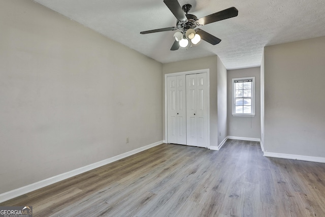 unfurnished bedroom with ceiling fan, light hardwood / wood-style flooring, a closet, and a textured ceiling