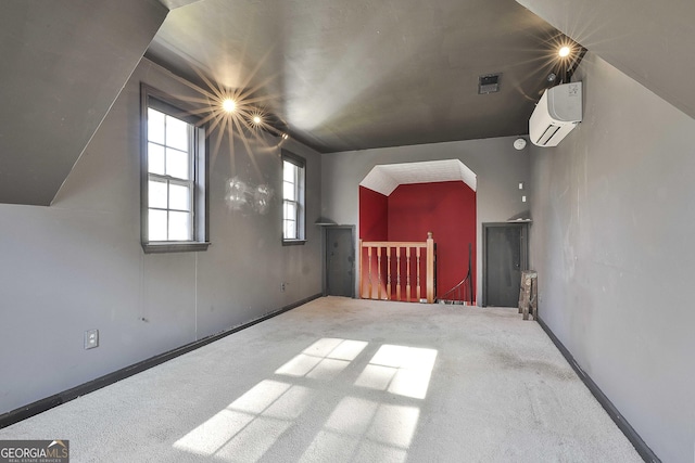 additional living space featuring lofted ceiling, an AC wall unit, and carpet