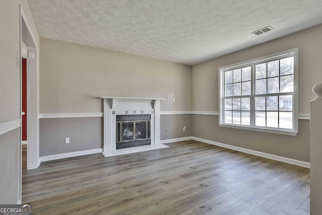 unfurnished living room with a tiled fireplace, light hardwood / wood-style floors, and a textured ceiling