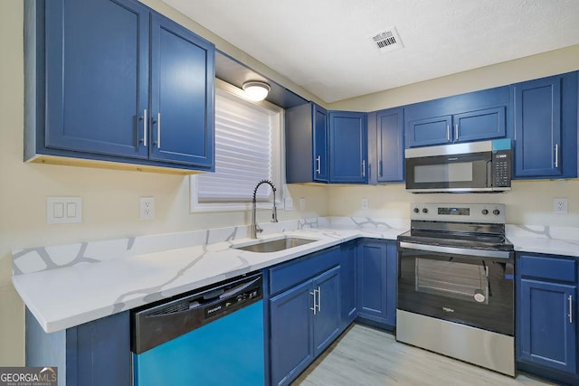 kitchen featuring appliances with stainless steel finishes, blue cabinetry, and sink