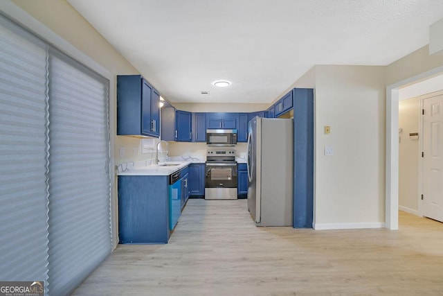 kitchen featuring sink, stainless steel appliances, light hardwood / wood-style floors, and blue cabinets