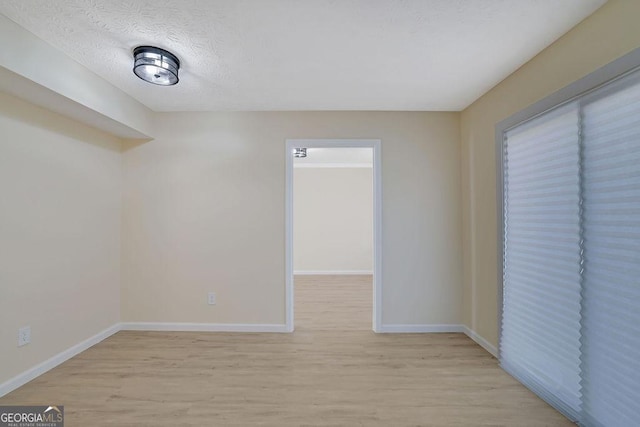 unfurnished room with a textured ceiling and light wood-type flooring