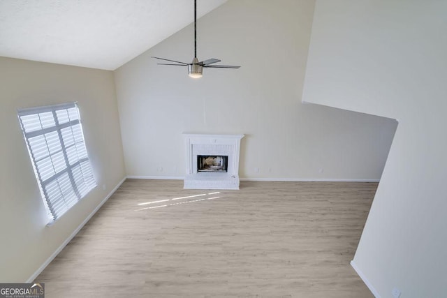 unfurnished living room featuring ceiling fan, high vaulted ceiling, light wood-type flooring, and a fireplace