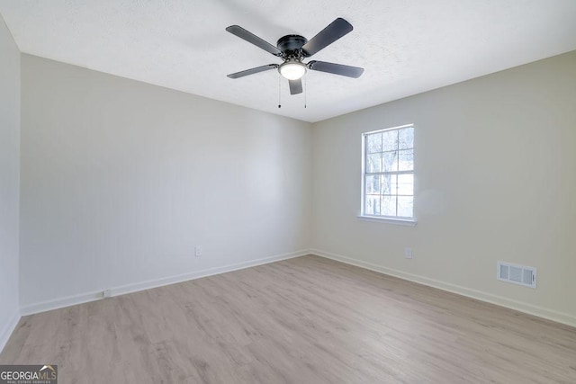 spare room featuring ceiling fan, light hardwood / wood-style floors, and a textured ceiling