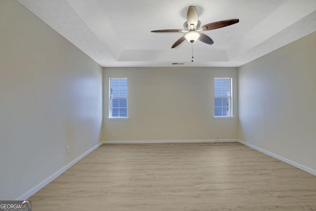 unfurnished room featuring a tray ceiling, light hardwood / wood-style flooring, and ceiling fan