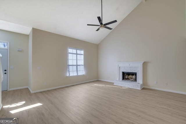 unfurnished living room with ceiling fan, high vaulted ceiling, light wood-type flooring, and a fireplace