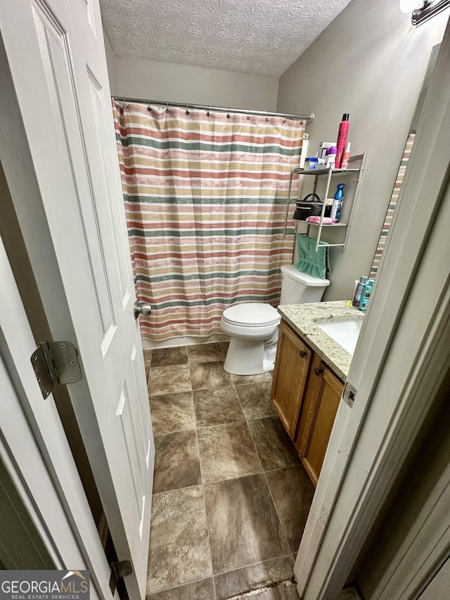 bathroom with vanity, toilet, and a textured ceiling