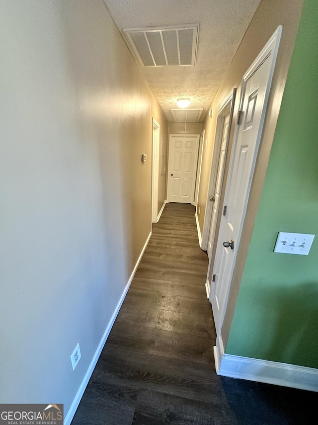 hallway with dark hardwood / wood-style floors and a textured ceiling