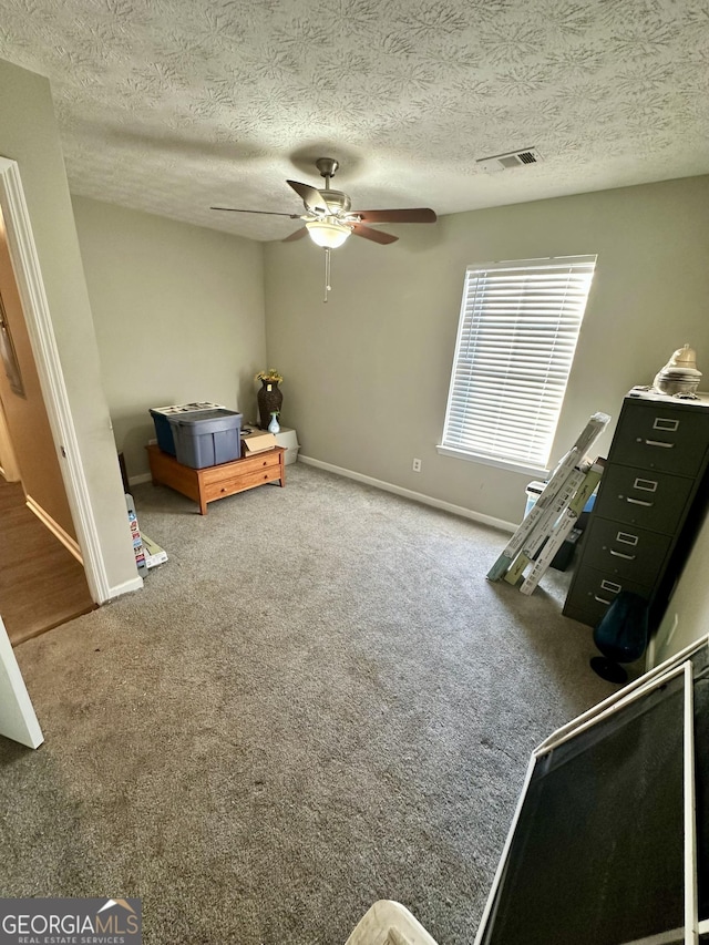 unfurnished bedroom featuring ceiling fan, carpet floors, and a textured ceiling