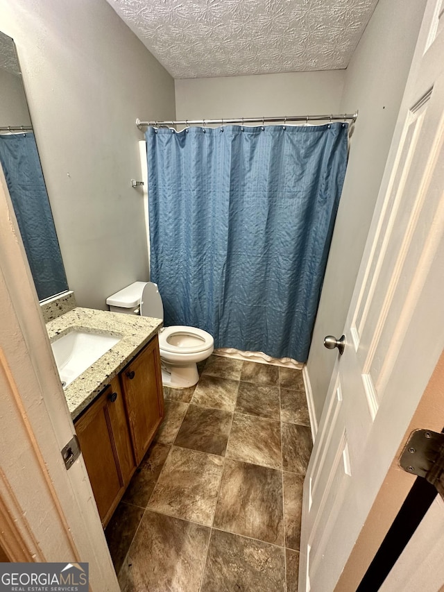 bathroom featuring vanity, walk in shower, a textured ceiling, and toilet