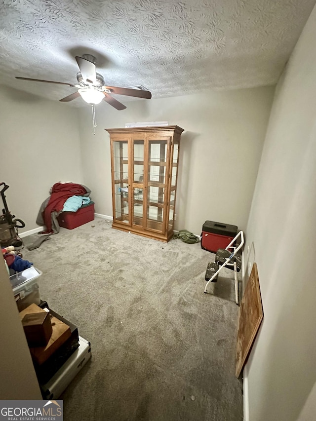 interior space with ceiling fan, carpet floors, and a textured ceiling