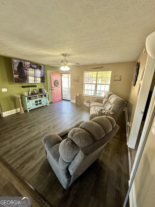 living room with ceiling fan, a textured ceiling, and dark hardwood / wood-style flooring