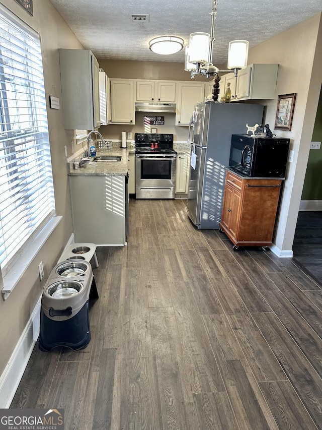 kitchen with dark wood-type flooring, sink, a textured ceiling, pendant lighting, and stainless steel appliances