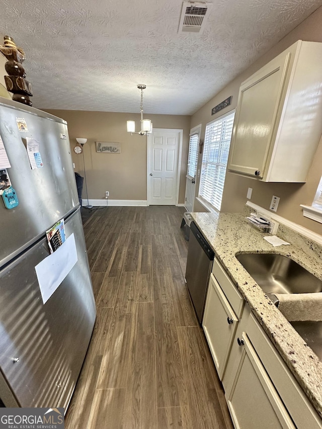 kitchen featuring light stone counters, a textured ceiling, dark hardwood / wood-style flooring, pendant lighting, and stainless steel appliances