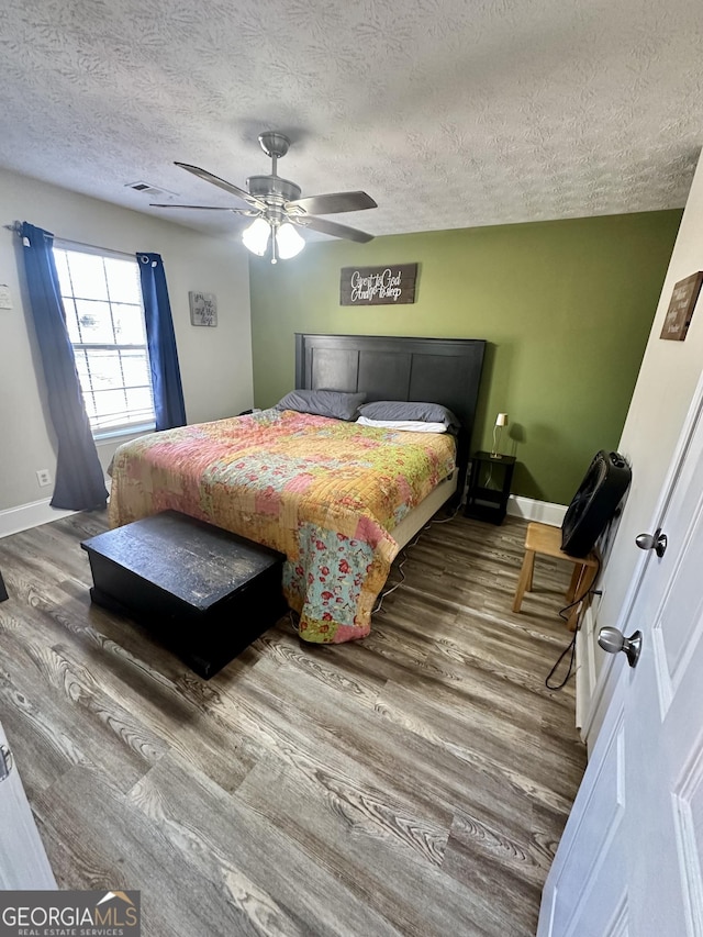 bedroom featuring ceiling fan, wood-type flooring, and a textured ceiling