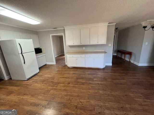 kitchen featuring dark wood-type flooring, a textured ceiling, white refrigerator, ornamental molding, and white cabinets