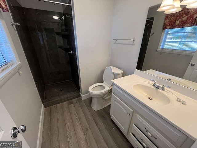 bathroom with vanity, hardwood / wood-style floors, toilet, and tiled shower