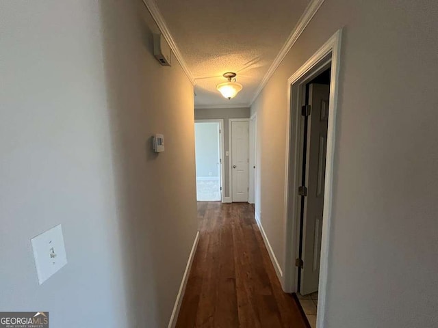 hallway with dark hardwood / wood-style flooring, ornamental molding, and a textured ceiling