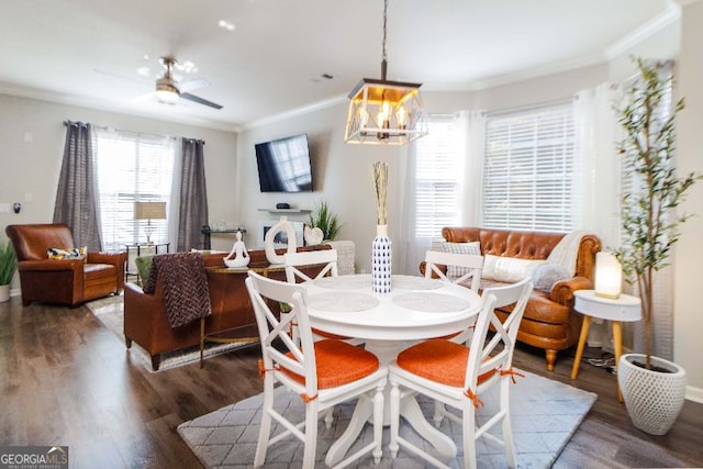 dining area with dark wood-type flooring, ornamental molding, and ceiling fan with notable chandelier