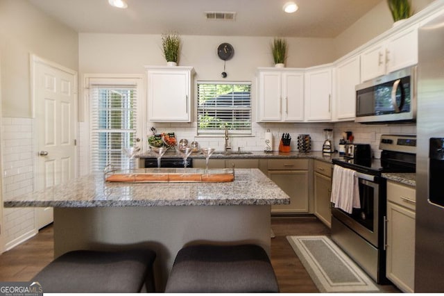 kitchen featuring stainless steel appliances, white cabinetry, light stone countertops, and sink